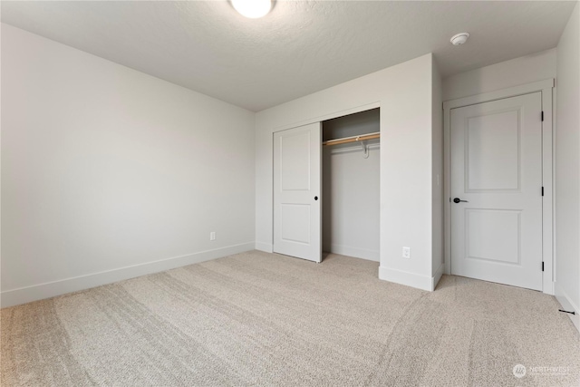 unfurnished bedroom with light colored carpet, a textured ceiling, and a closet