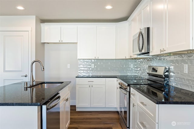 kitchen with white cabinetry, appliances with stainless steel finishes, sink, and dark stone counters