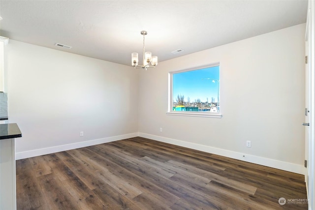 unfurnished dining area with dark hardwood / wood-style floors and a notable chandelier