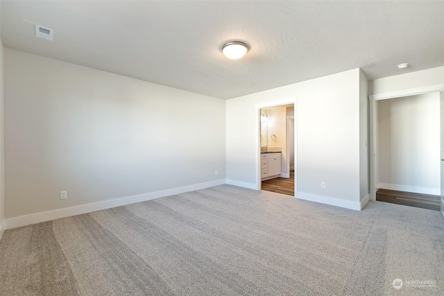 unfurnished bedroom with connected bathroom and carpet floors