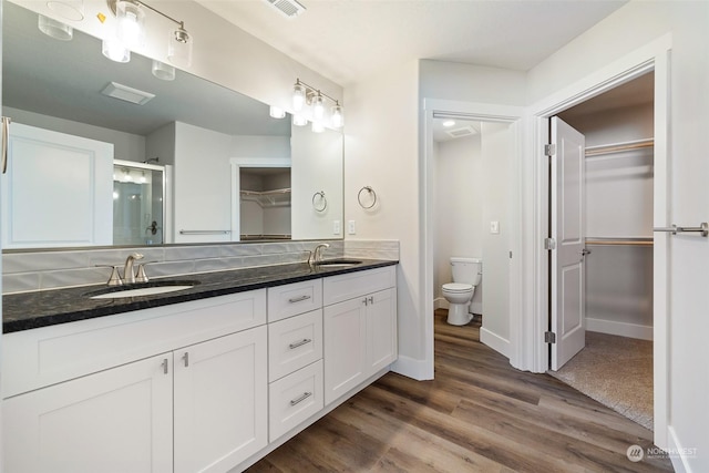 bathroom with vanity, toilet, a shower with shower door, and wood-type flooring