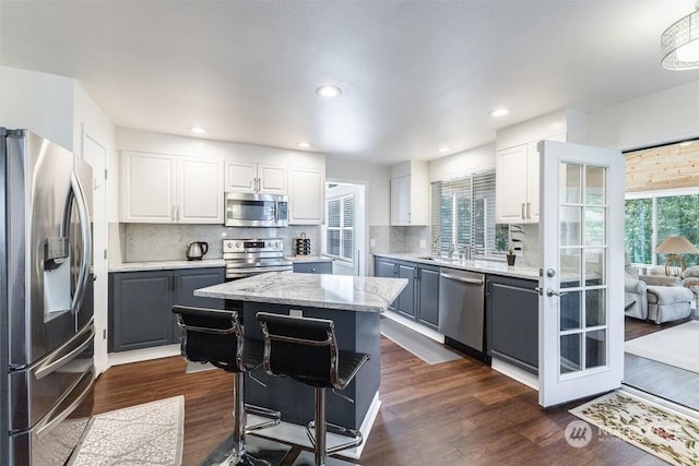 kitchen with a center island, dark hardwood / wood-style flooring, decorative backsplash, white cabinets, and appliances with stainless steel finishes