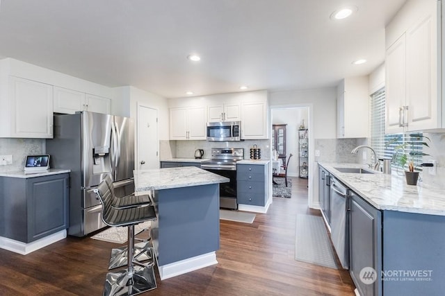 kitchen featuring sink, a kitchen island, dark hardwood / wood-style flooring, white cabinetry, and stainless steel appliances