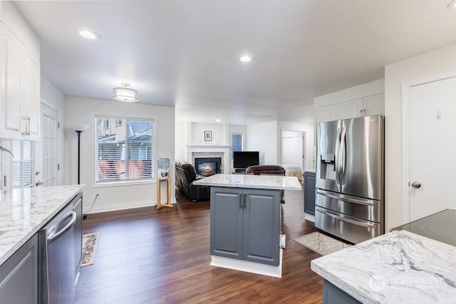 kitchen with gray cabinetry, light stone countertops, white cabinets, a kitchen island, and appliances with stainless steel finishes