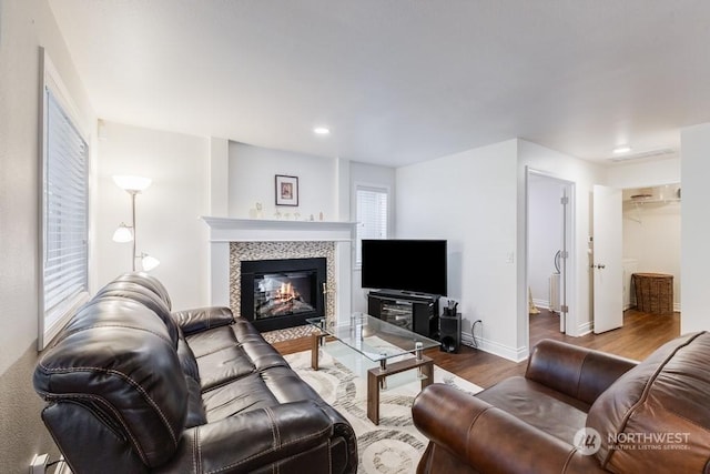 living room with wood-type flooring and a tiled fireplace