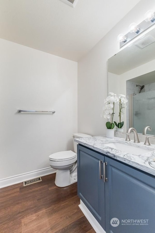 bathroom featuring hardwood / wood-style floors, vanity, a shower with shower door, and toilet