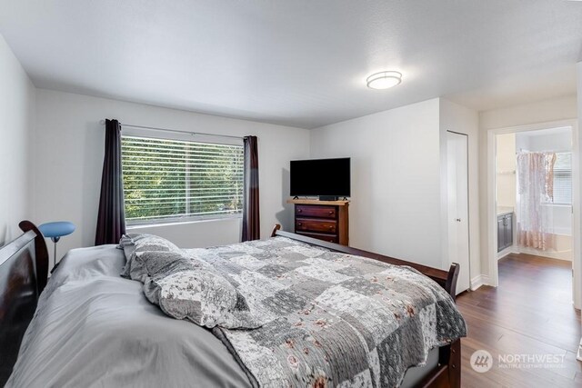 bedroom featuring dark wood-type flooring and ensuite bath