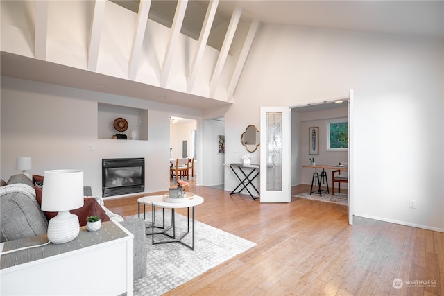 living room with light hardwood / wood-style flooring and high vaulted ceiling