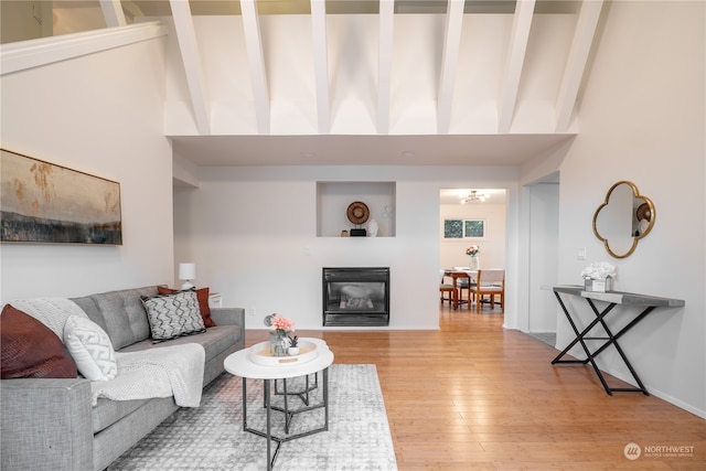 living room with beamed ceiling, light hardwood / wood-style flooring, and high vaulted ceiling