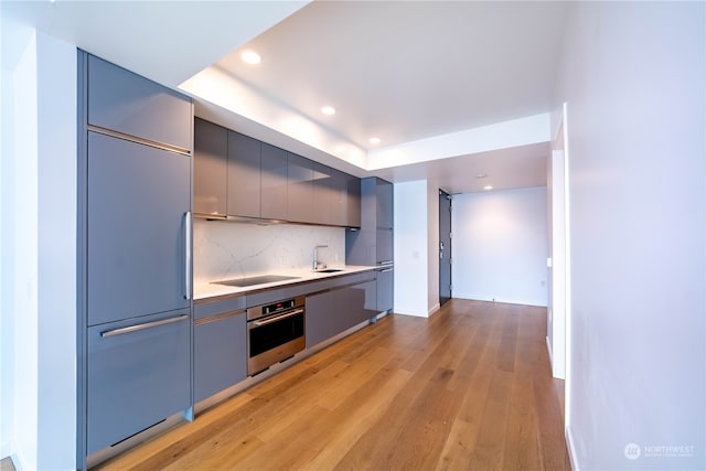 kitchen featuring stainless steel oven, light hardwood / wood-style flooring, built in fridge, and decorative backsplash