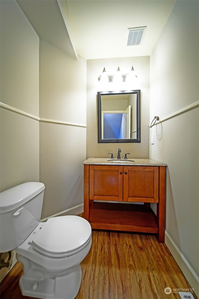 bathroom with vanity, toilet, and wood-type flooring