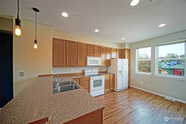 kitchen with decorative light fixtures, white appliances, light hardwood / wood-style floors, sink, and kitchen peninsula