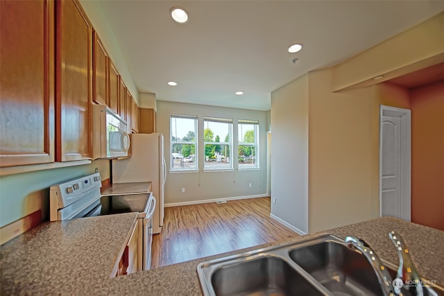 kitchen with light wood-type flooring, electric range, and sink