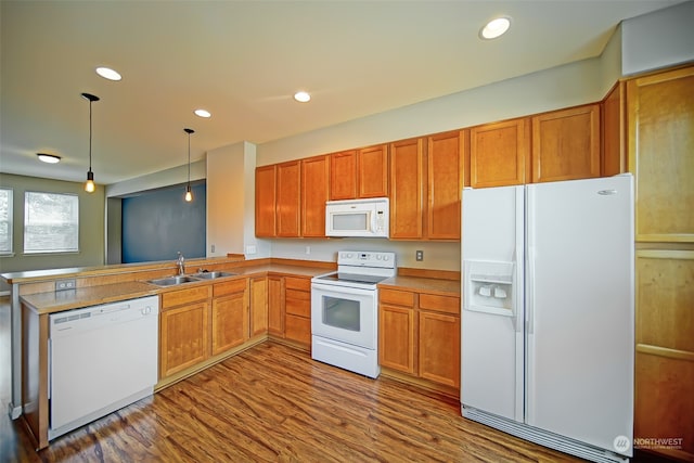 kitchen featuring dark hardwood / wood-style floors, decorative light fixtures, white appliances, kitchen peninsula, and sink