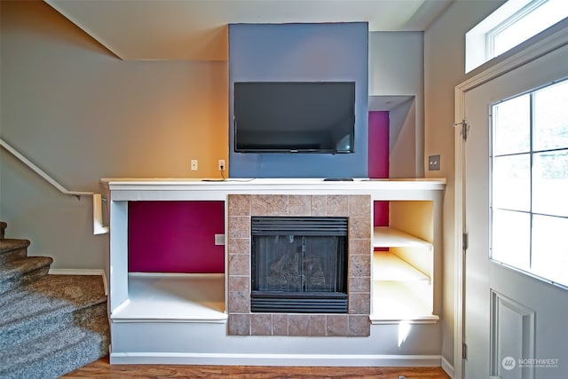 living room with a tile fireplace and hardwood / wood-style flooring