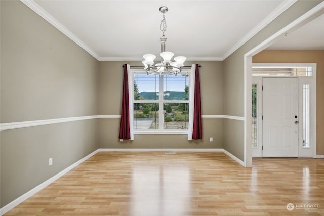 foyer with an inviting chandelier, light wood-type flooring, and ornamental molding