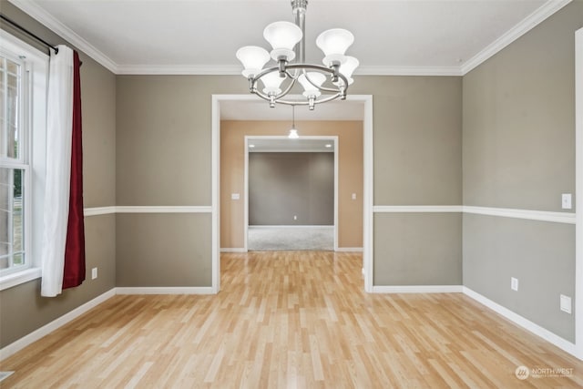 spare room featuring light hardwood / wood-style flooring, crown molding, and a chandelier