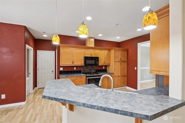 kitchen featuring kitchen peninsula, stainless steel range with electric stovetop, pendant lighting, and light hardwood / wood-style flooring