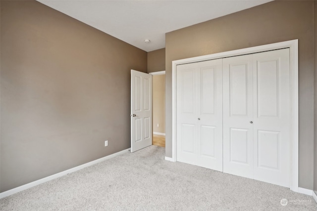 unfurnished bedroom with light carpet and a closet