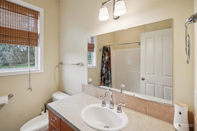 bathroom with vanity, walk in shower, a healthy amount of sunlight, and toilet