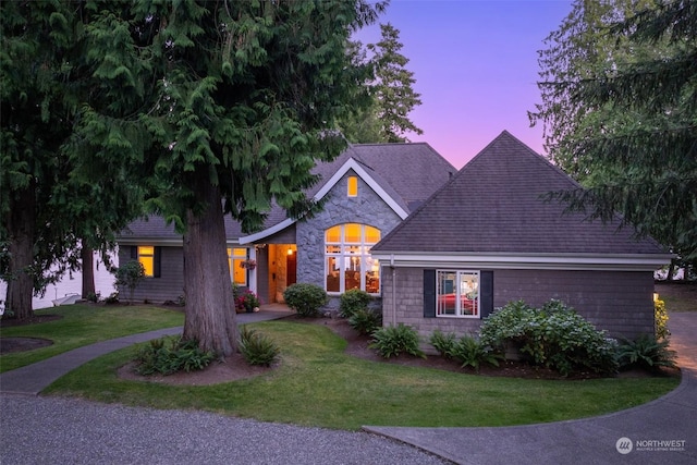 view of front of home with stone siding, a shingled roof, and a front yard