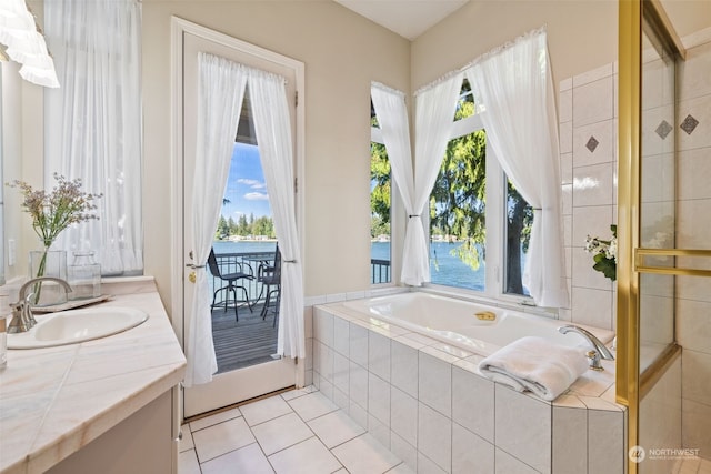 bathroom featuring tiled bath, tile patterned floors, a water view, and vanity