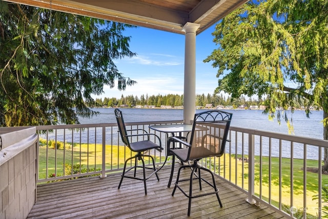 wooden terrace with a water view and a lawn