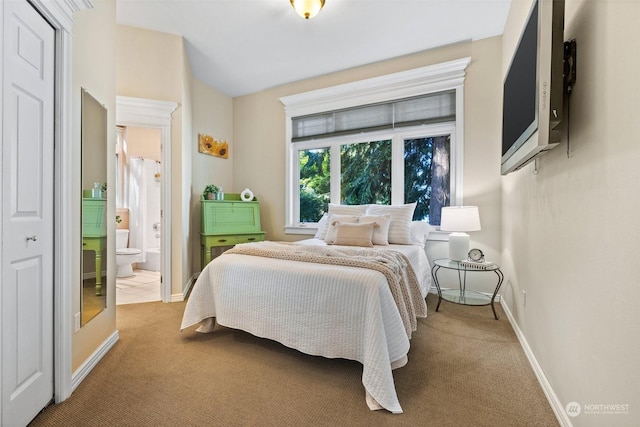 bedroom with carpet flooring, ensuite bath, and baseboards