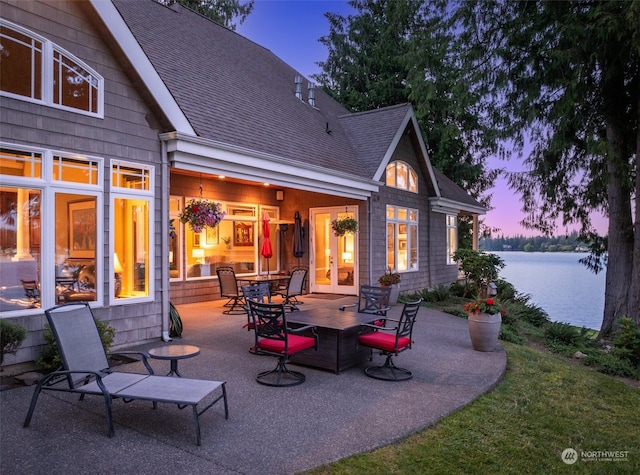 patio terrace at dusk featuring a water view