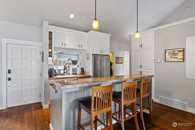 kitchen featuring high end fridge, white cabinetry, lofted ceiling, and dark wood-type flooring