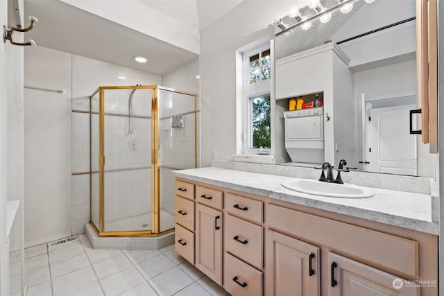 bathroom with tile patterned flooring, stacked washer / drying machine, vanity, and a shower with shower door