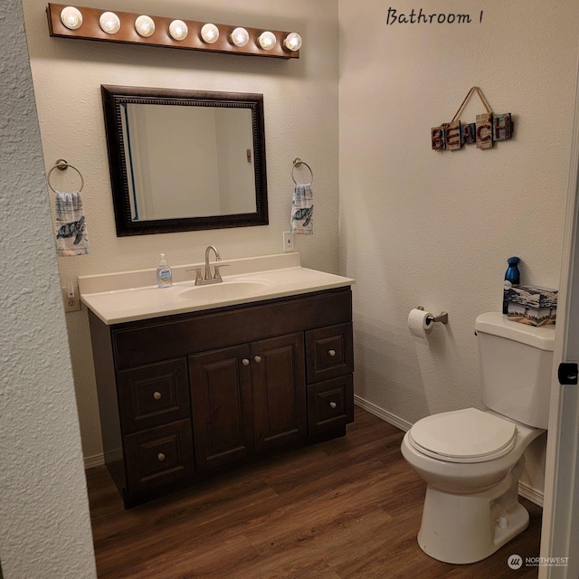 bathroom with hardwood / wood-style flooring, vanity, and toilet