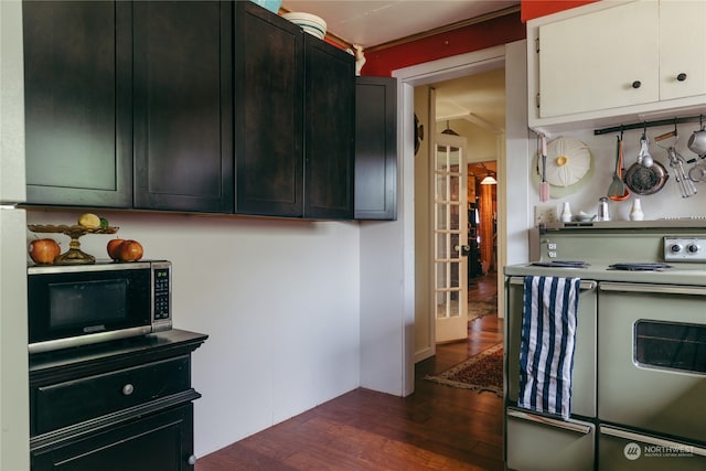 kitchen with dark wood-type flooring, electric range, black oven, and ornamental molding