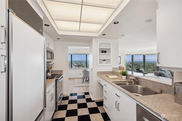 kitchen featuring sink, appliances with stainless steel finishes, white cabinets, and tile patterned floors