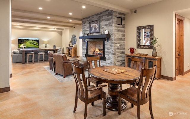 carpeted dining area with a stone fireplace