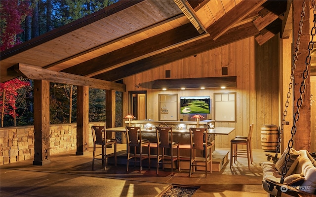 bar with lofted ceiling with beams, wood ceiling, and wood walls