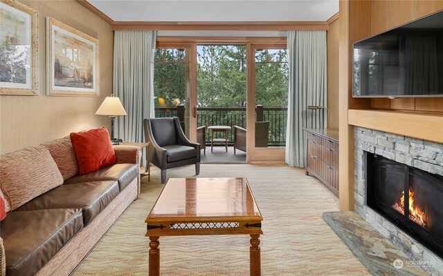 carpeted living room with a stone fireplace and crown molding