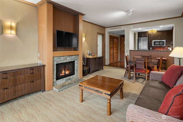 living room with crown molding and a stone fireplace