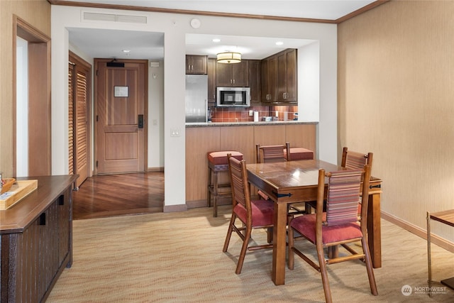 dining room with crown molding and light hardwood / wood-style flooring