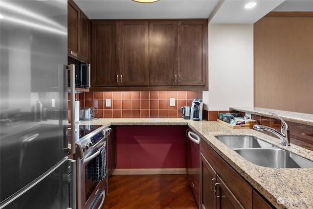 kitchen featuring light stone countertops, appliances with stainless steel finishes, dark wood-type flooring, sink, and backsplash