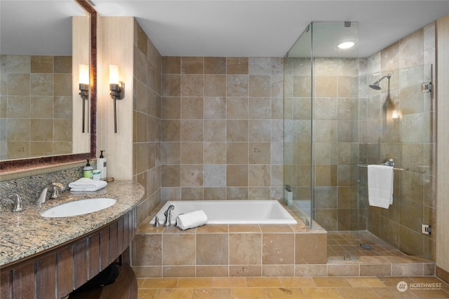 bathroom featuring independent shower and bath, vanity, and tile walls