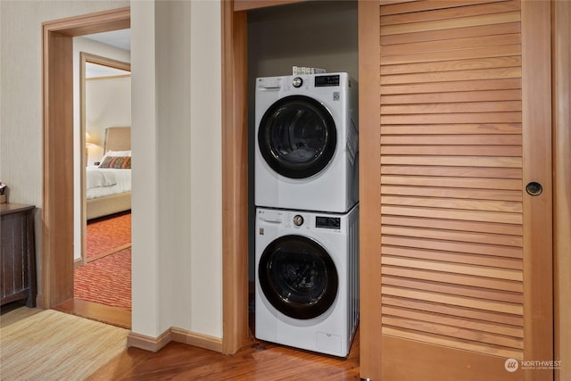 laundry room featuring light hardwood / wood-style floors and stacked washing maching and dryer