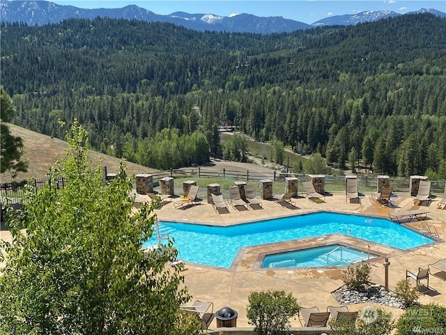 view of pool featuring a mountain view, a patio, and a hot tub