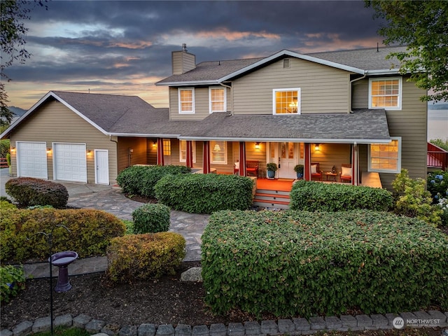 view of front of house with a porch, a shingled roof, a chimney, and a garage