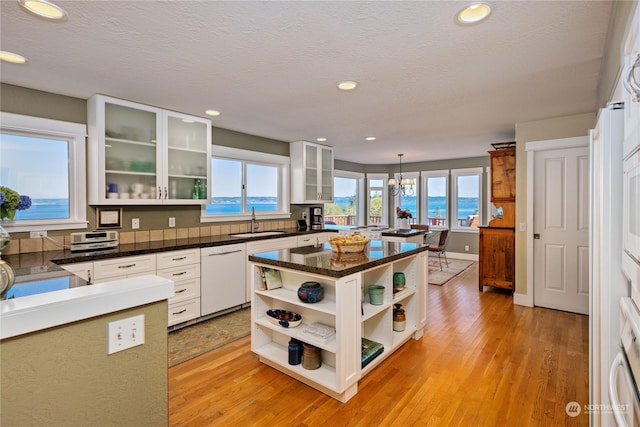 kitchen featuring a sink, light wood-type flooring, open shelves, and dishwasher