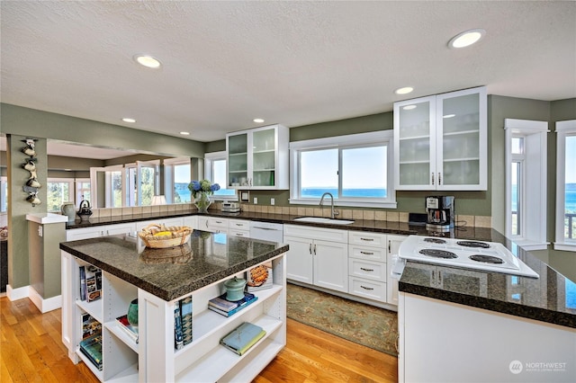 kitchen with open shelves, a sink, and light wood-style floors