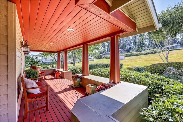 wooden deck featuring covered porch and a yard