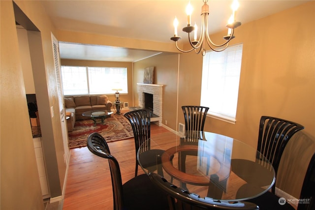 dining area with light hardwood / wood-style floors, a chandelier, and a fireplace