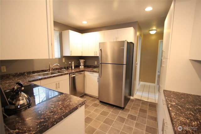 kitchen with dark stone countertops, sink, white cabinetry, dark tile patterned floors, and appliances with stainless steel finishes