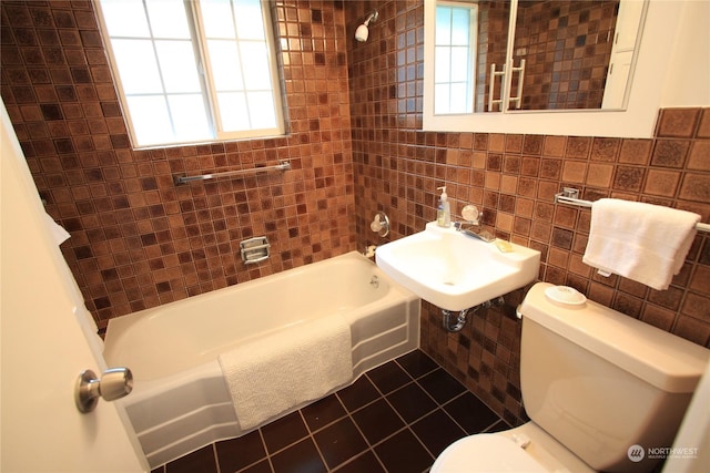 full bathroom with toilet, tiled shower / bath combo, tile walls, tile patterned floors, and sink